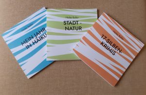 Die Bücher "Mein Jahr in Haiku", "Stadt-Natur" und "17-Silben-Krimis" von Heike Baller liegen auf einem beigefarbenen Hintergrund.